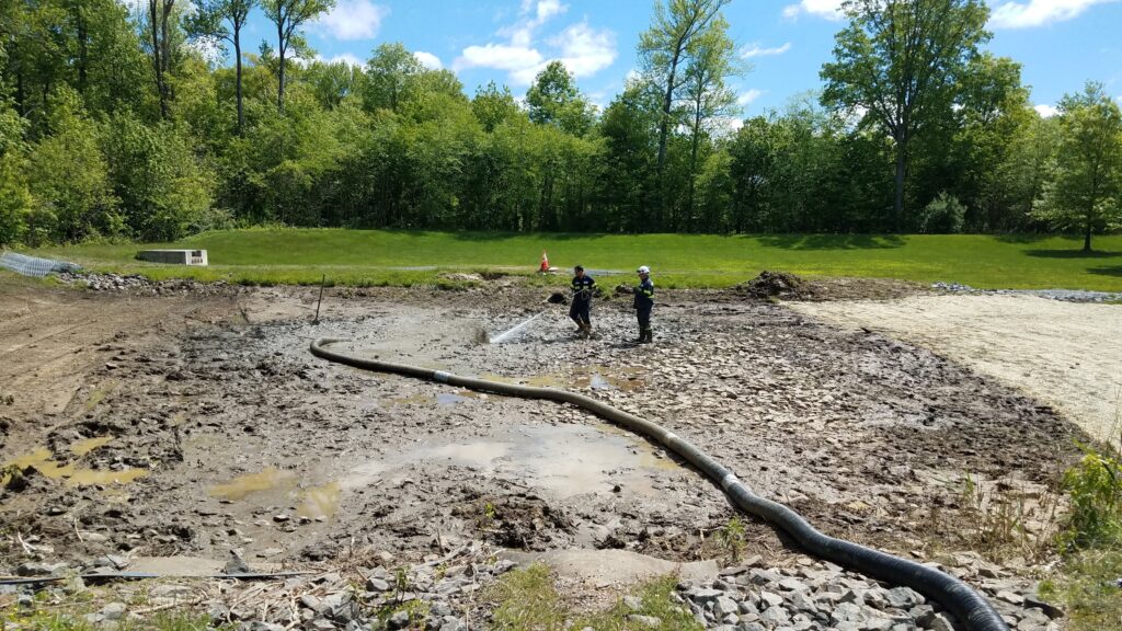 Workers performing sediment removal in a detention basin to maintain water quality and prevent buildup.