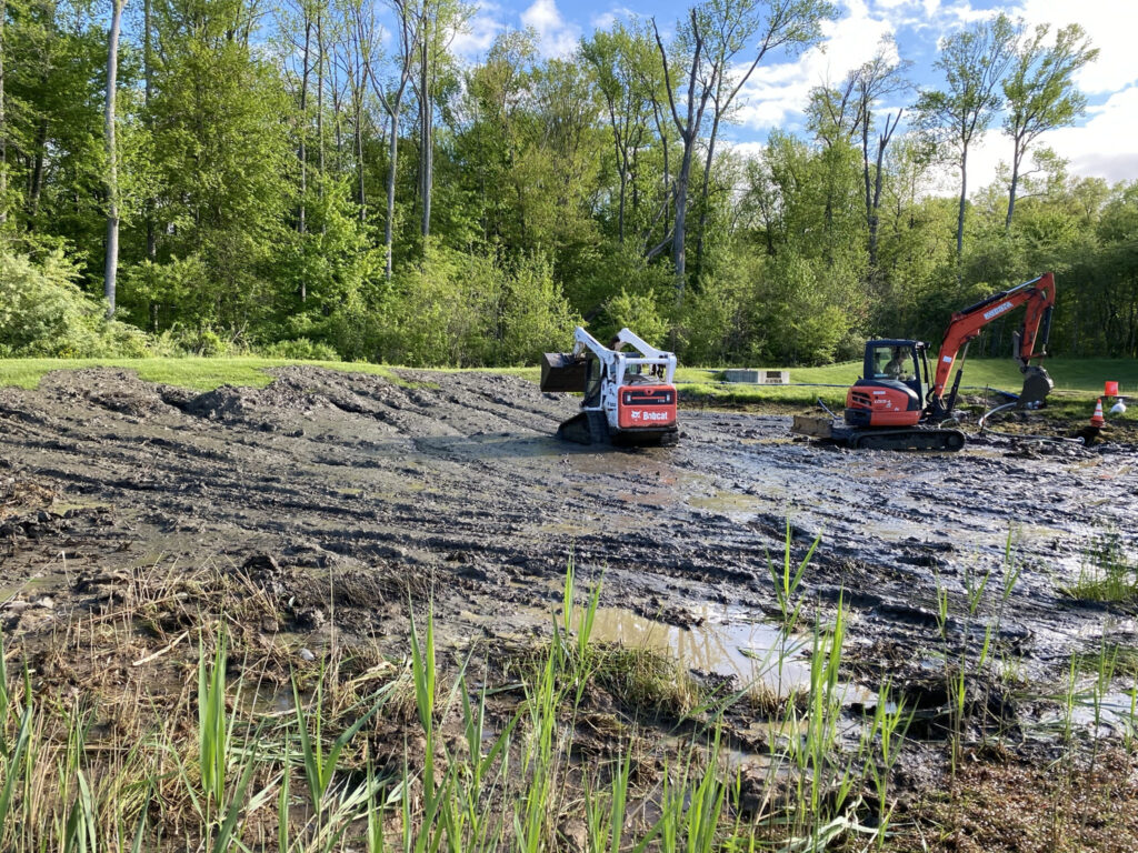 Excavators removing sediment from a stormwater pond as part of sediment control and pond maintenance.